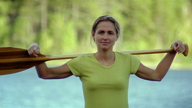 中镜头倾斜的肖像女人拿着桨在肩膀上视频下载
