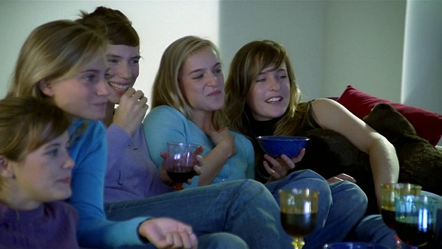 5个女人坐在沙发上看电视/吃喝/聊天+大笑视频素材