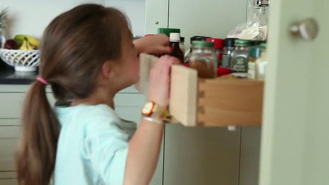 美国缅因州雅茅斯的一个女孩(6-7)从厨房储藏室里拿香草罐视频下载