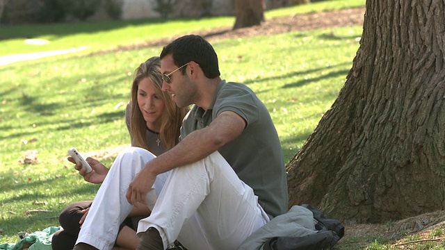 两位学生坐在校园草坪上使用手机，伯利恒，宾夕法尼亚州，美国视频下载