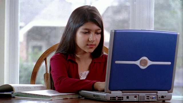 中等身材的女孩在笔记本电脑上做作业/翻课本视频素材