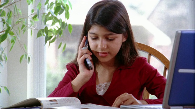 近距离的女孩做家庭作业，用手机聊天/放大翻课本视频素材