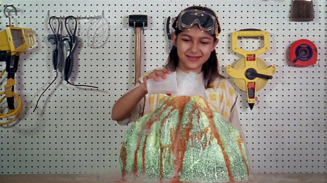 中拍女孩在棚屋里制作火山模型，微笑着看着从火山“喷发”的干冰，摆姿势给CAM拍照视频素材