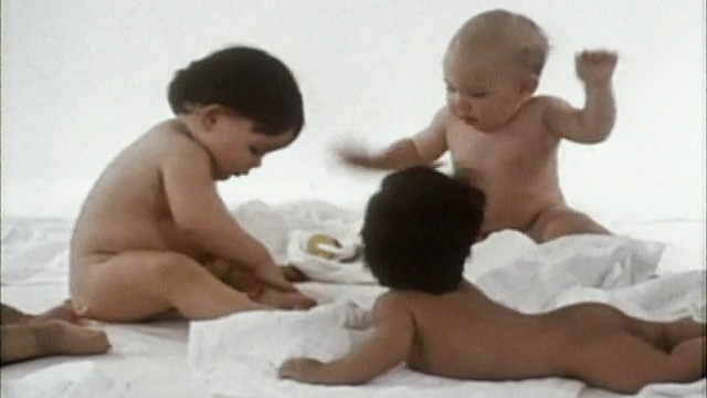 1985年，在白色背景下，中景拍摄赤裸的婴儿坐在白色毯子上玩耍视频下载