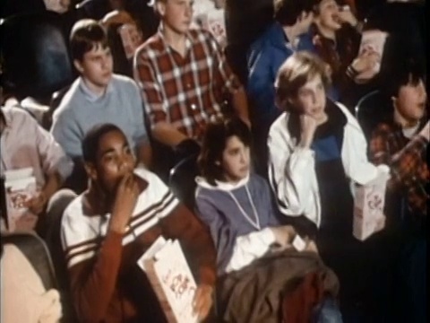 1985高角度中镜头坐在电影院吃爆米花的青少年视频下载