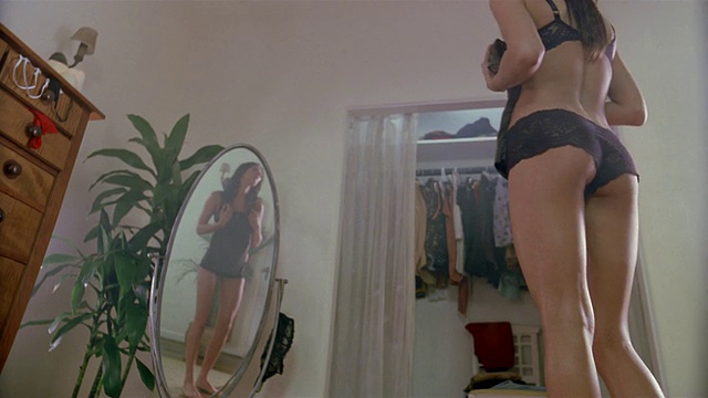 低角度中镜头女人穿着内衣站在镜子前拿着背心/扔掉它视频下载