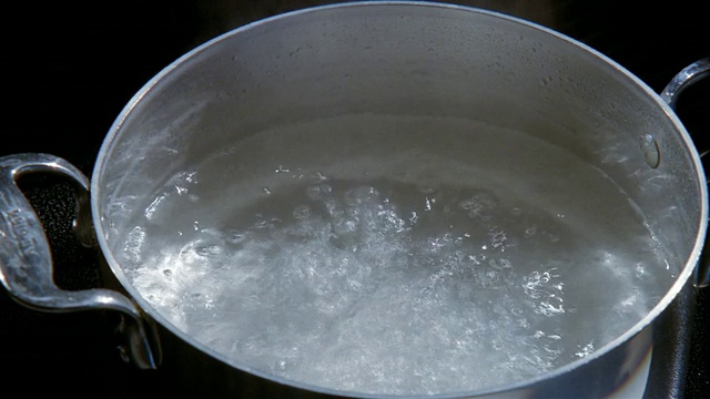 高角度把手从沸水锅中取出盖子/将盐倒入锅中视频素材