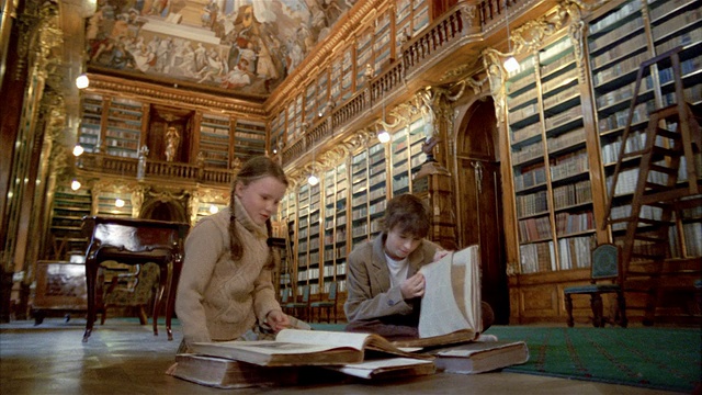布拉格斯特拉霍夫修道院的哲学堂图书馆里，低角度中镜头的女孩和男孩在读书视频购买