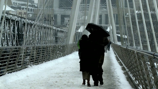 英国伦敦，人们在暴风雪中穿过亨格福德人行桥视频下载