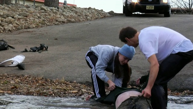 美国威斯康辛州新伦敦，一名警察和一名女子将一名男子从河里拖上岸视频素材