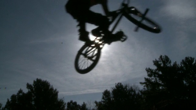 SLO MO WS剪影两个小轮车自行车跳跃，阳光在背景/杰克逊维尔，佛罗里达，美国视频下载