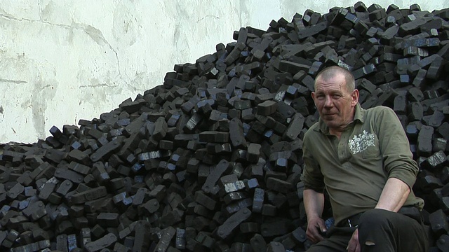 德国柏林，一名成年男子坐在煤堆旁的肖像视频下载