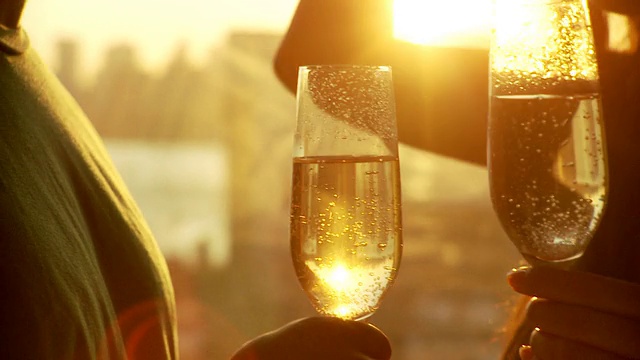 在日落时分，一对年轻的夫妇站在窗边喝香槟，布鲁克林，纽约，美国纽约州视频下载