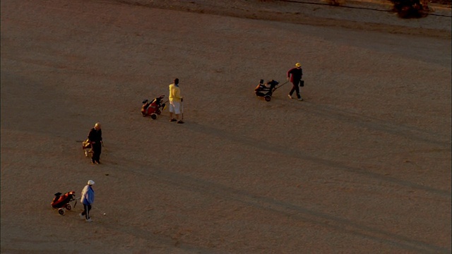 4名高尔夫球手和狗在日落，Coober Pedy，澳大利亚南部的高尔夫球场视频素材