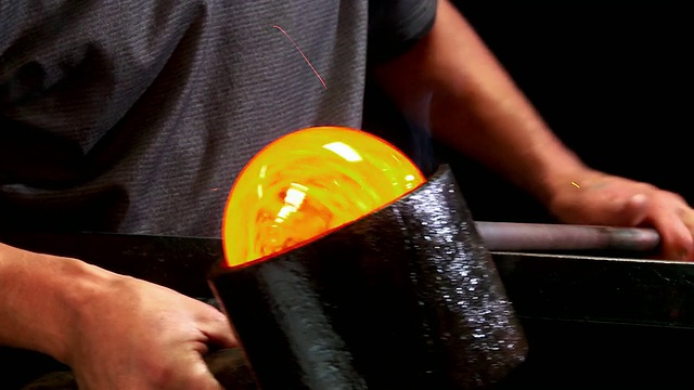 美国加州圣巴巴拉，用樱桃木模具塑造玻璃，CU艺术家的手在长凳边缘滚动熔融的玻璃视频下载