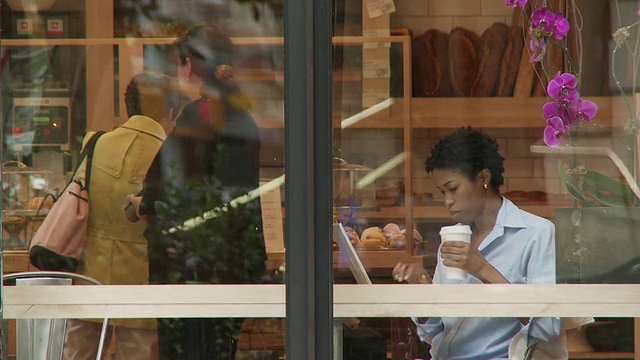 年轻女子在咖啡馆使用笔记本电脑，人们在纽约，美国。视频素材
