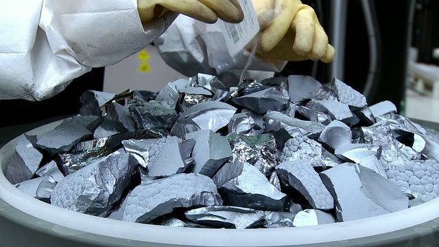 美国俄勒冈州希尔斯伯勒太阳能制造工厂Solarworld, cuzo MS实验室的技术人员将小颗粒硅片撒在大硅片堆上，在晶体生长炉的石英坩埚中，用于Czochralski工艺视频素材