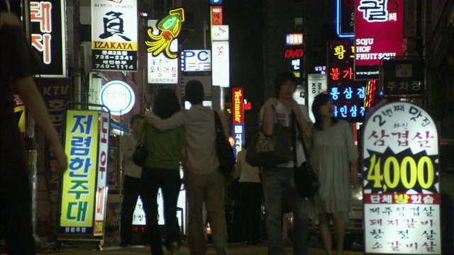 韩国首尔，夜间行人在市中心街道上行走，汽车在镜头前行驶视频素材
