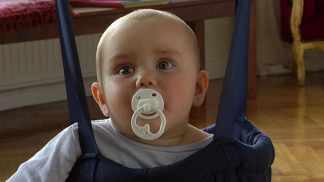 CU宝宝(8-9个月)坐在婴儿保镖里吮吸奶嘴/德国柏林视频素材