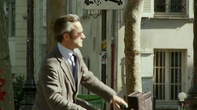 法国巴黎，商人走出地铁站，骑着自行车离开修道院广场视频素材