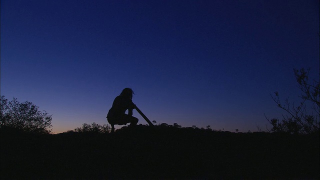 WS剪影的人演奏迪吉里杜管在黄昏，爱丽丝斯普林斯，北领地，澳大利亚视频下载