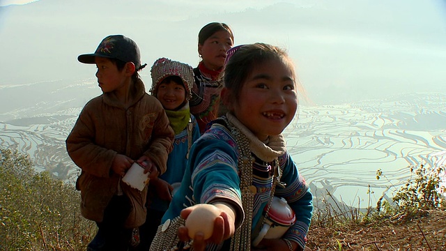 中国云南元阳，四个哈尼孩子拿着锅子，背景是稻田视频下载