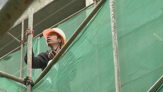 MS LA Young建筑工人在脚手架上使用对讲机，云南昆明，中国视频下载