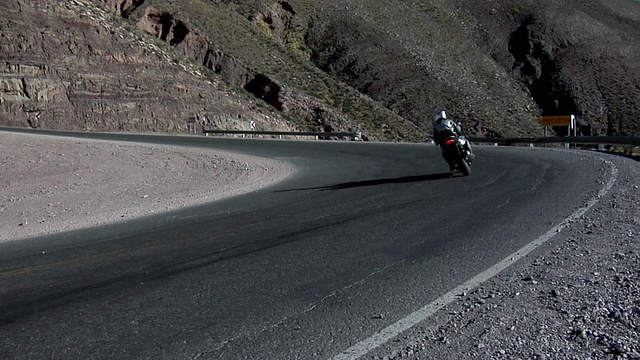 WS后视图的两名男子在公路上骑摩托车穿越沙漠景观与落基山脉，萨斯奎斯，Jujuy，阿根廷视频下载