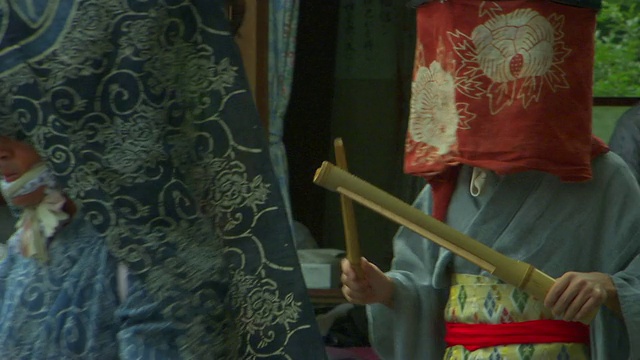在日本的秋天节日里，人们穿着传统的日本服装，有些人戴着面纱和头饰，一起敲打木棍视频下载