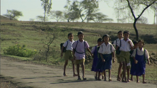 印度德里地区，年轻的女孩和男孩穿着校服背着背包走在乡村的土路上视频素材