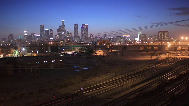 T/L WS HA黄昏到夜晚的城市景观与火车轨道在前景，洛杉矶，加利福尼亚州，美国视频下载