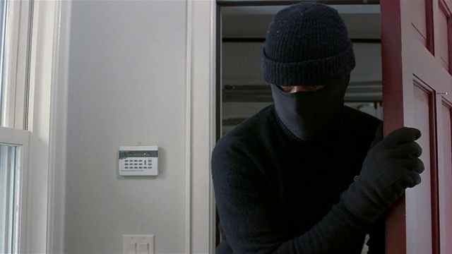 中景窃贼戴着滑雪面具潜入屋内/墙上的防盗报警器视频下载