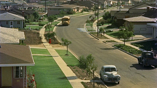 1955年，一名身着红裙的妇女走在美国洛杉矶郊区的人行道上视频素材