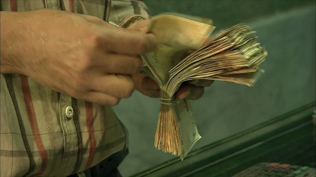 伊朗伊斯法罕大巴扎，一名男子在货币兑换处数钱视频下载