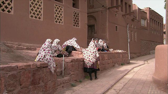 伊朗Abyaneh，戴着头巾的妇女聚集在房子外面视频素材