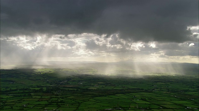 空中全景拍摄的阳光穿过雨云在绿色景观/科克郡，爱尔兰视频下载