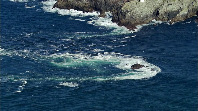 航拍中拍奥赛岛海岸的激流/缩小宽拍奥赛岛和灯塔/赫布里底群岛，苏格兰视频下载