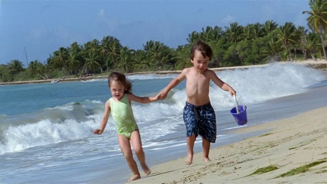 中等镜头的年轻男孩和女孩在海滩上跑步视频下载