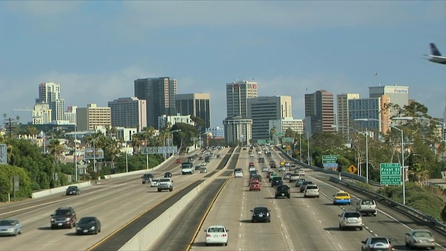 多车道高速公路向市中心行驶，商业飞机在美国加州圣地亚哥高速公路上降落视频下载
