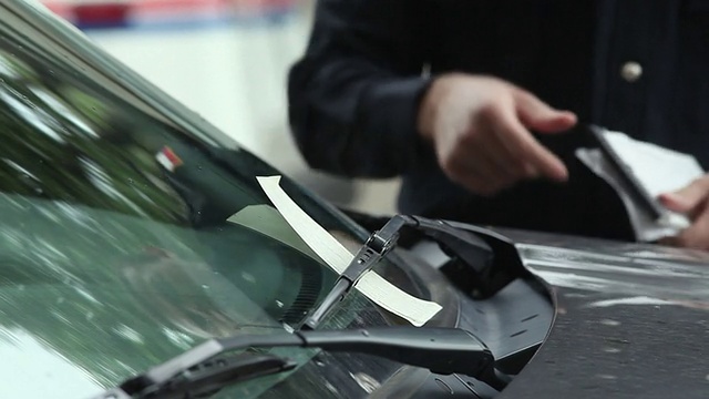 一名警察将停车罚单放在挡风玻璃上，德克萨斯州达拉斯，美国视频下载