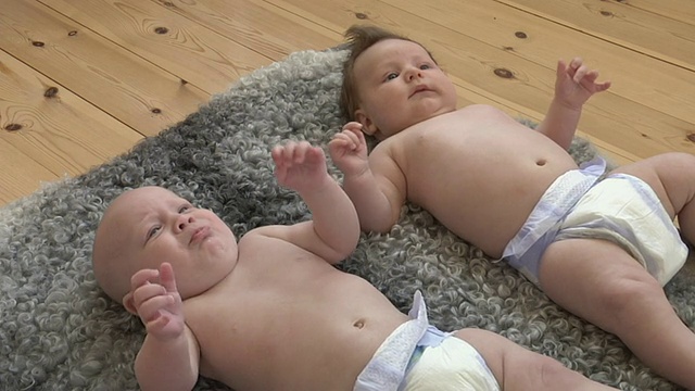 一名女婴(6-11个月)和一名男婴(2-5个月)躺在瑞典加夫勒堡县的地毯上视频素材