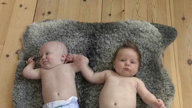 一名女婴(6-11个月)和一名男婴(2-5个月)躺在瑞典加夫勒堡县的地毯上视频素材
