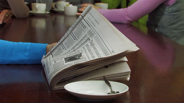 MS Woman drinking coffee while reading newspaper, women in background /开普敦，西开普敦，南非视频素材