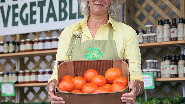 在美国弗吉尼亚州里士满的农贸市场，一位成熟的妇女拿着一盒西红柿视频素材