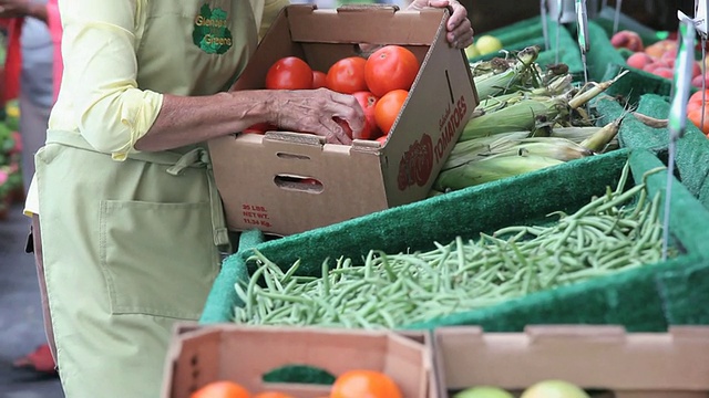 在美国弗吉尼亚州里士满的农贸市场，一个成熟的女人拿着一盒西红柿视频素材