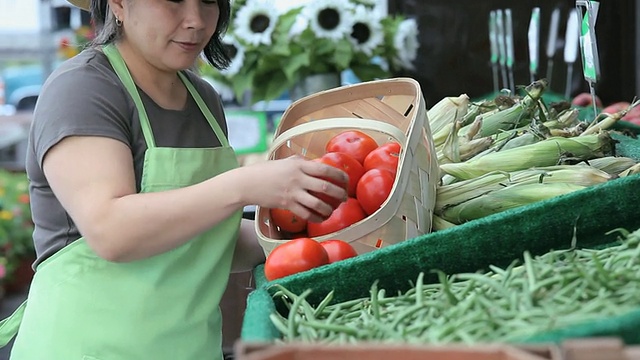 在美国弗吉尼亚州里士满的农贸市场，一名小贩正在整理一盒西红柿视频素材