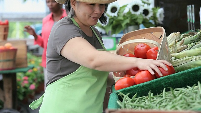 在美国弗吉尼亚州里士满的农贸市场，一名摊贩正在整理一盒西红柿视频素材