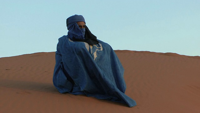 WS ZO Tuareg戴着传统的靛蓝色围巾坐在沙丘上，Erg Chebbi，摩洛哥视频下载