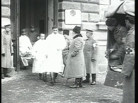 1915蒙太奇B/W医院工作人员用担架将受伤士兵从医院大楼抬到等候的车厢/俄罗斯视频素材