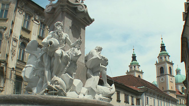 斯洛文尼亚卢布尔雅那，弗朗西斯科·罗巴设计的MS巴洛克罗巴喷泉(卡尼奥拉三河喷泉)，以圣尼古拉斯大教堂塔楼为背景视频素材